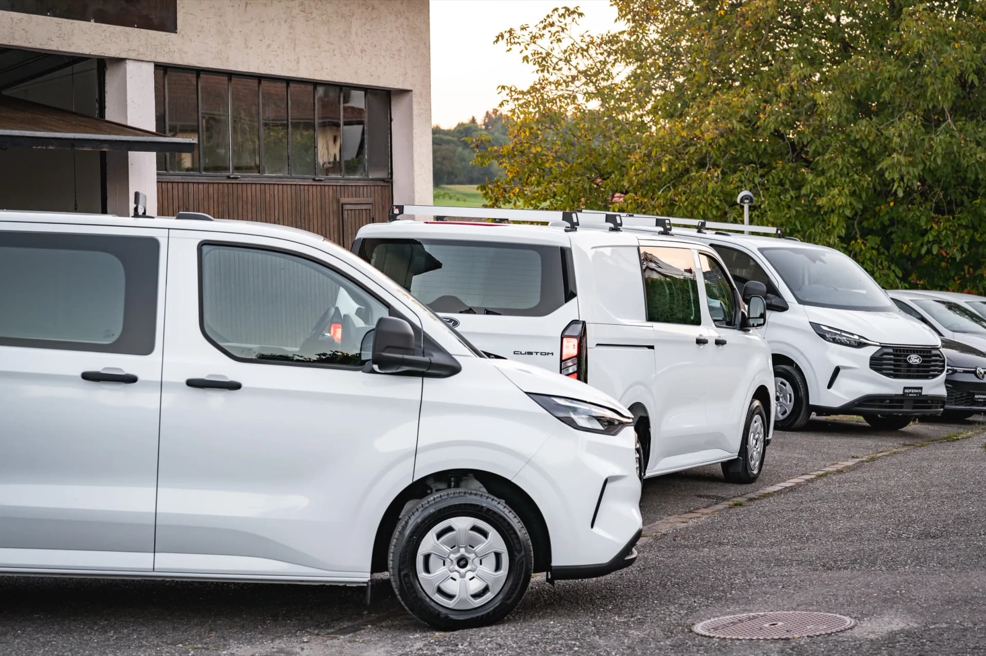 Mehrere importierte Ford Transit Custom in einer Reihe vor der Werkstatt